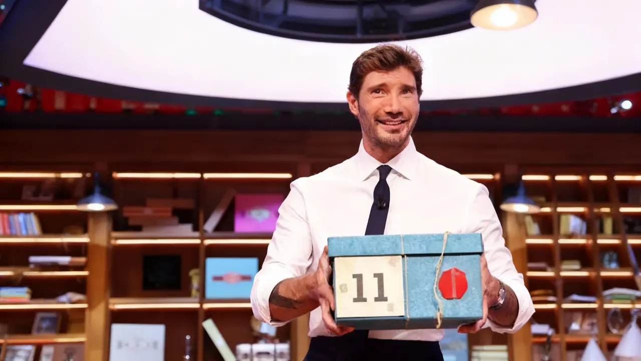 Un conduttore televisivo tiene in mano una scatola numerata sul set di un programma TV