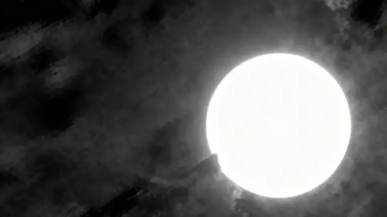 Oggetto luminoso circondato da nubi scure in un cielo notturno