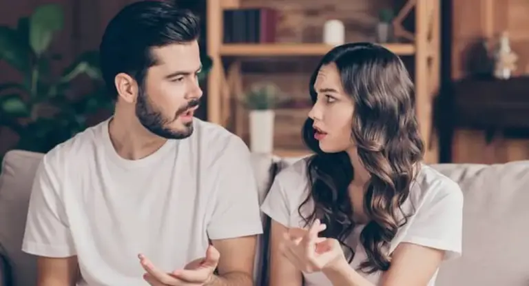 Due persone sedute su un divano mentre discutono animatamente