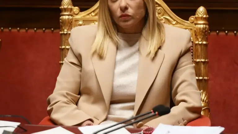 Una persona seduta su una sedia dorata in un'aula istituzionale