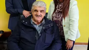 Tre persone posano sorridenti in un ambiente interno con parete gialla