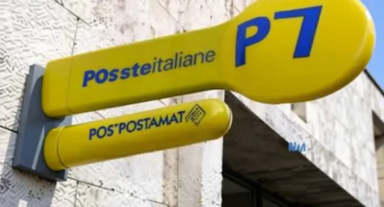 Insegna gialla di un ufficio Postepay e Postamat su un edificio in pietra
