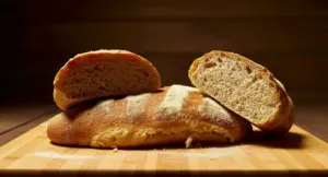 Pane integrale tagliato a metà su un tagliere in legno