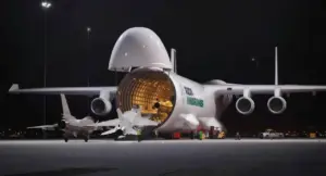 Un grande aereo cargo aperto mentre carica jet su una pista illuminata di notte