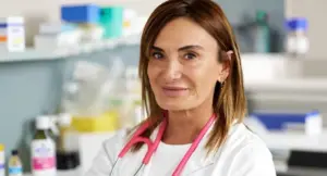 Una donna in camice bianco con stetoscopio rosa in un laboratorio medico