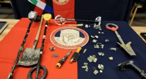 Attrezzatura da scavo e reperti archeologici su un tavolo con bandiera dei Carabinieri
