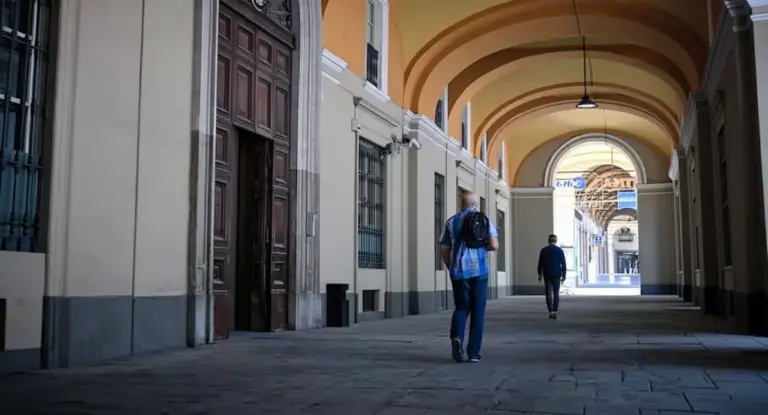 Due persone camminano sotto un portico in una città