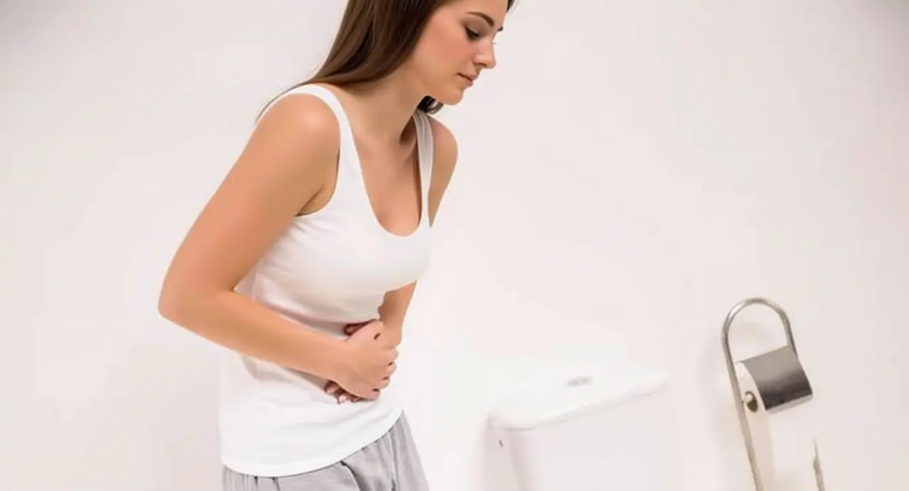 Persona con dolore addominale vicino a un water in bagno